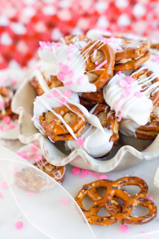 Valentine's Day Pretzel Bites recipe is so simple to make for any holiday, it's no wonder they're a classic! Two pretzels that are stuffed with a peanut butter filling and dipped in melted white chocolate coating. Great for gifts and parties!