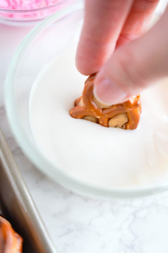 Dipping the pretzels in the white chocolate for the Valentine's Day Pretzel Bites recipe