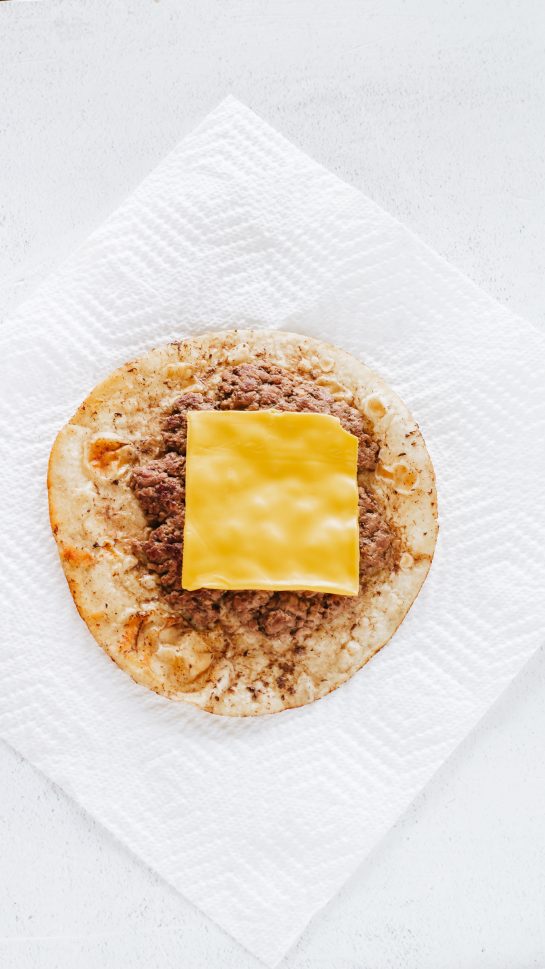 Topping the ground beef or ground turkey for the Big Mac Tacos recipe with a slice of cheese