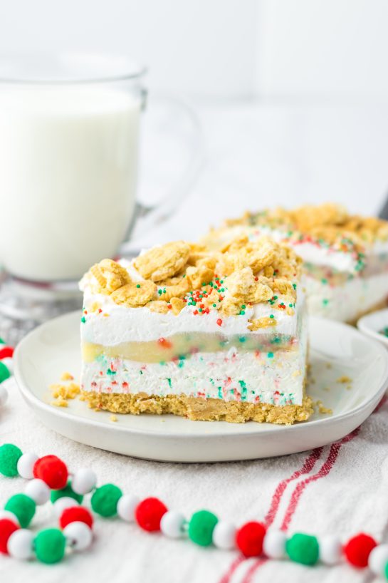 Christmas Cookie Lush is the perfect holiday dessert.  This is no-bake, so it makes for a quick dessert when you are entertaining. Layers of vanilla cream cookies and sprinkles, a cheesecake layer, finished off with a pudding layer, whipped topping, crushed cookies and sprinkles to look like the perfect Christmas Cookie dessert. 