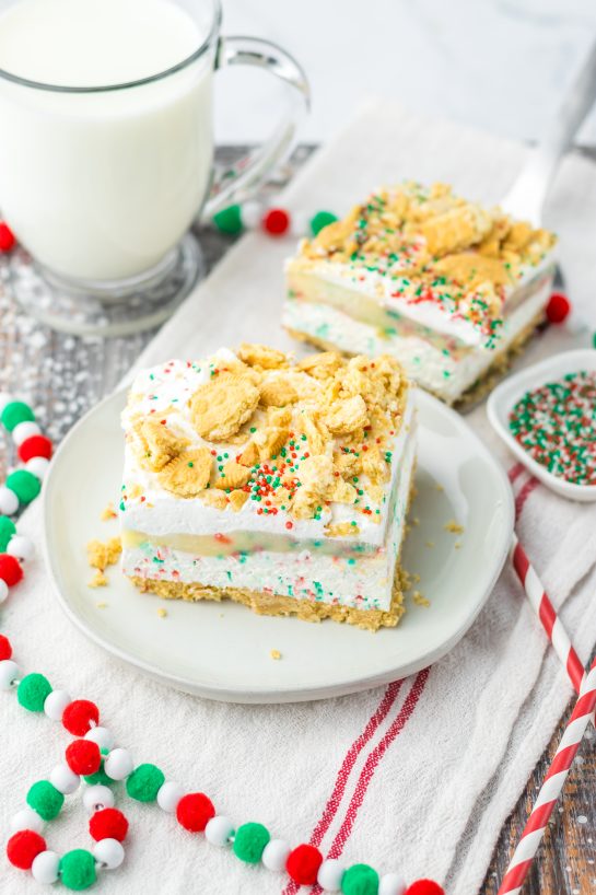Christmas Cookie Lush recipe is the perfect holiday dessert.  This is no-bake, so it makes for a quick dessert when you are entertaining. Layers of vanilla cream cookies and sprinkles, a cheesecake layer, finished off with a pudding layer, whipped topping, crushed cookies and sprinkles to look like the perfect Christmas Cookie dessert. 