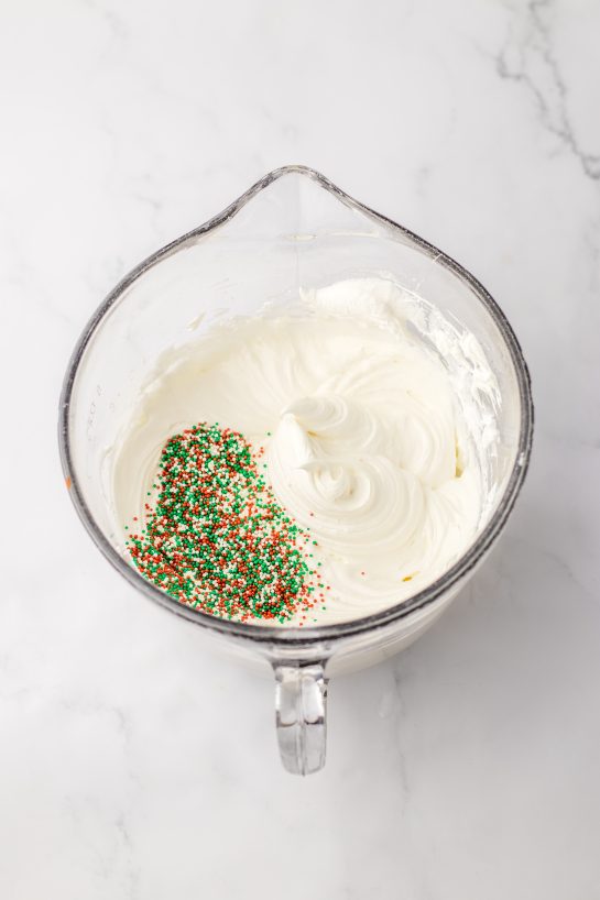 Mixing the cheesecake layer with sprinkles for the Christmas Cookie Lush recipe 