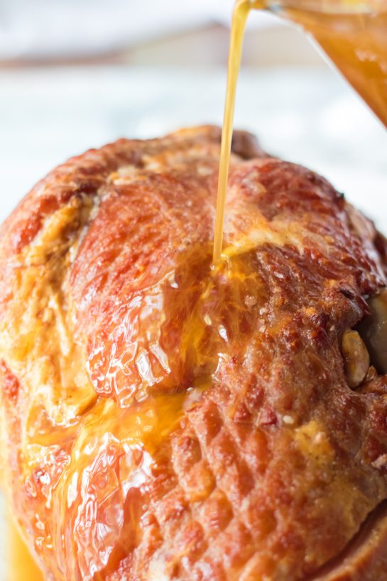 Close-up of pouring the glaze over Christmas ham for Christmas dinner.