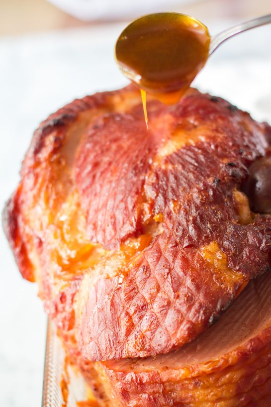 Pouring the glaze over Christmas ham for Christmas dinner.