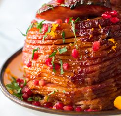 It isn’t Christmas without a gorgeous, glazed Christmas ham recipe and this one is perfect!  Orange juice, brown sugar, honey and cinnamon make up a delicious glaze for this ham.  Orange zest, pomegranate seeds and parsley give this ham it’s festive colors.  This ham smells and tastes like Christmas Day and is sure to become your new holiday ham.