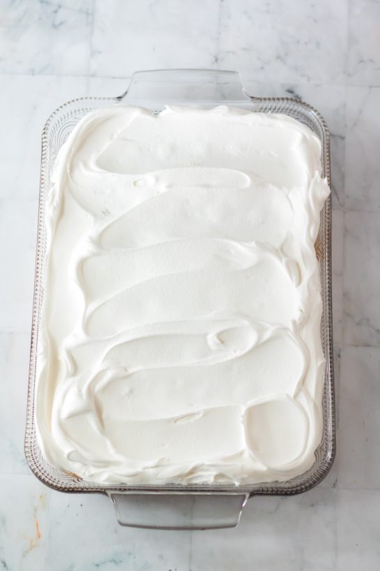 Photo of frosting the Christmas Poke Cake with the whipped cream frosting