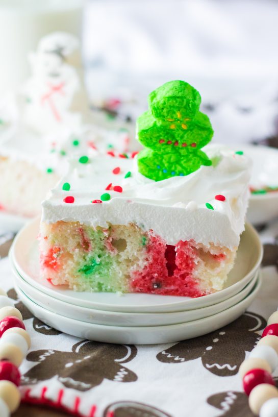 Photo of a decorated slice of the finished Christmas Poke Cake recipe for the perfect holiday dessert