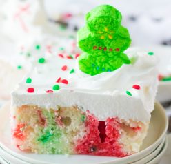 Christmas Poke Cake recipe is the easy, delicious, festive cake that everyone will love! White cake mix, green and red Jell-o and whipped cream make up this adorable cake! It gets topped with holiday sprinkles & marshmallows. Kids will love to help decorate this holiday Cake!