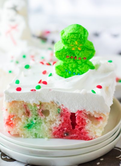 Christmas Poke Cake recipe is the easy, delicious, festive cake that everyone will love! White cake mix, green and red Jell-o and whipped cream make up this adorable cake! It gets topped with holiday sprinkles & marshmallows. Kids will love to help decorate this holiday Cake!