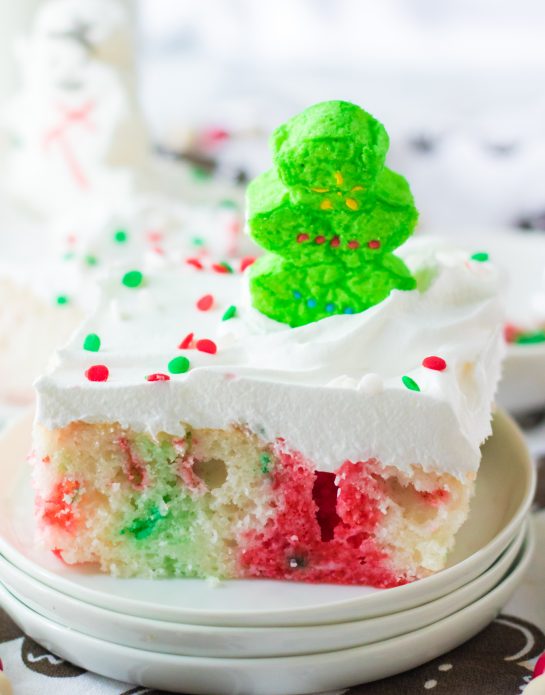 Christmas Poke Cake recipe is the easy, delicious, festive cake that everyone will love! White cake mix, green and red Jell-o and whipped cream make up this adorable cake! It gets topped with holiday sprinkles & marshmallows. Kids will love to help decorate this holiday Cake!