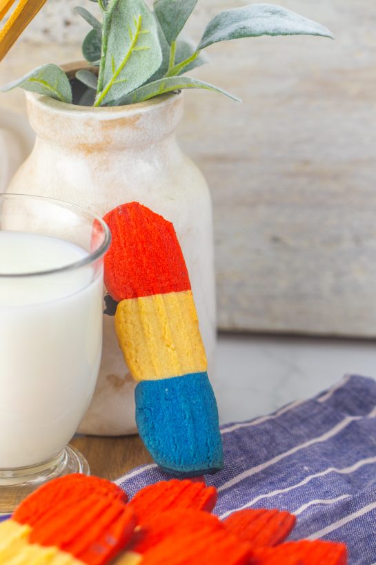 This recipe for Bomb Pop Cookies is not only so tasty but so cute for the 4th of July! These are the perfect dessert to bring for those red, white and blue holidays. Bursting with Sugar cookie flavors with hints of cherry flavoring in the red and blueberry flavoring in the blue, using Jello! These were so fun to make and were a huge hit for your outdoor parties!
