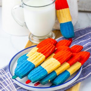 This recipe for Bomb Pop Cookies is not only so tasty but so cute for the 4th of July! These are the perfect dessert to bring for those red, white and blue holidays. Bursting with Sugar cookie flavors with hints of cherry flavoring in the red and blueberry flavoring in the blue, using Jello! These were so fun to make and were a huge hit for everybody involved!