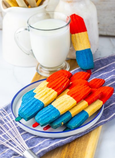 This recipe for Bomb Pop Cookies is not only so tasty but so cute for the 4th of July! These are the perfect dessert to bring for those red, white and blue holidays. Bursting with Sugar cookie flavors with hints of cherry flavoring in the red and blueberry flavoring in the blue, using Jello! These were so fun to make and were a huge hit for everybody involved!