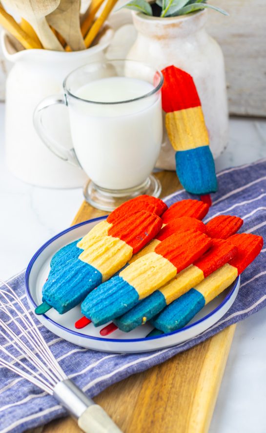 This recipe for Bomb Pop Cookies is not only so tasty but so cute for the 4th of July! These are the perfect dessert to bring for those red, white and blue holidays. Bursting with Sugar cookie flavors with hints of cherry flavoring in the red and blueberry flavoring in the blue, using Jello! These were so fun to make and were a huge hit for everybody involved!