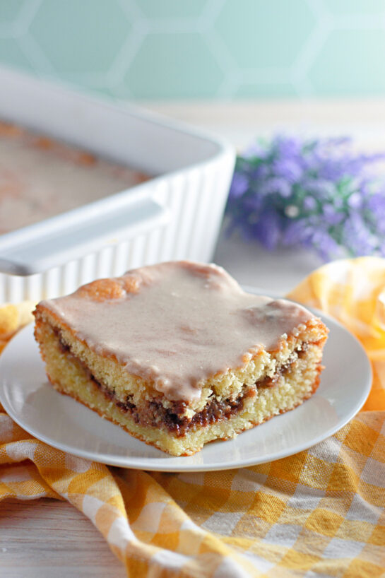 This Honey Bun Cake recipe made with yellow cake mix, sour cream, and chopped pecans is a Southern-inspired dessert that tastes just like a warm bakery honey bun! Perfectly moist, swirled with brown sugar and cinnamon, this easy doctored cake mix recipe comes together in minutes — no fancy baking skills required.