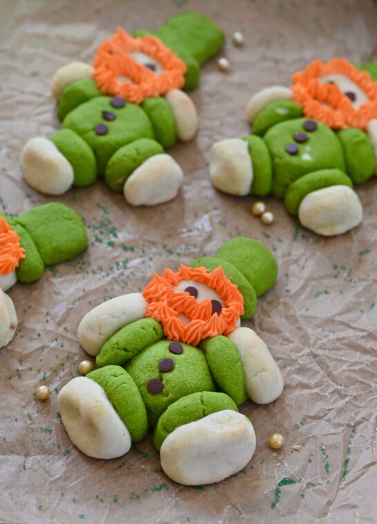 Lucky Leprechaun Cookies made with green and white sugar cookie dough, mini chocolate chip buttons, and fluffy orange frosting beards. These cute, chubby St. Patrick's Day leprechaun cookies are a fun, festive, and easy holiday dessert recipe perfect for parties, kids, and St. Patty'sDay baking. 